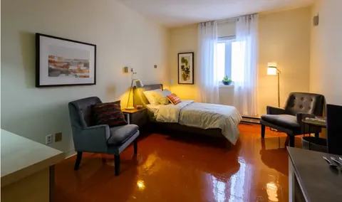 Bedroom with a single bed, two armchairs, lamps and framed landscape art