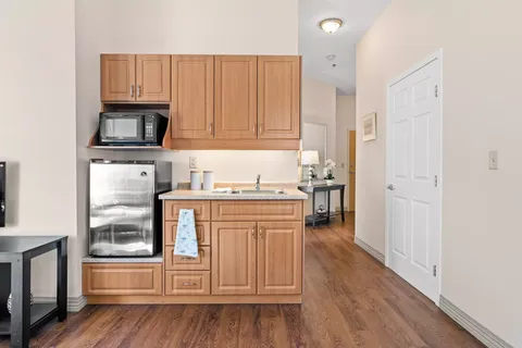 Kitchenette with wood cabinets, microwave and refrigerator