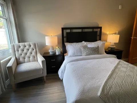 Bedroom with a bed, armchair, bedside tables and lamps