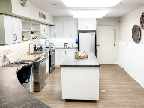 Kitchen with white cabinets, an island, a stove and a refrigerator