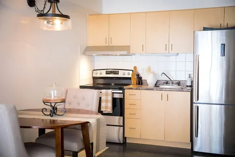 Suite kitchen with stove, refrigerator, cabinets and dining table.