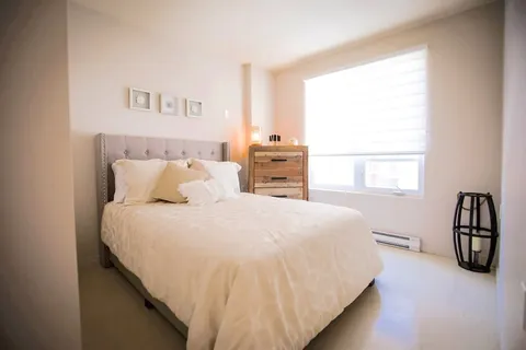 Bedroom with double bed, bedside cabinet and window blinds.