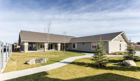 Single-storey building beside a lawn and paved walkway