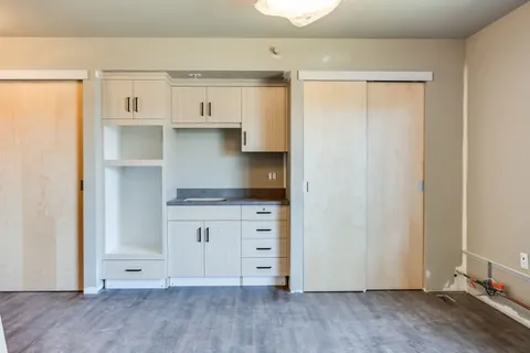 Empty room with a kitchenette and sliding wooden closet doors