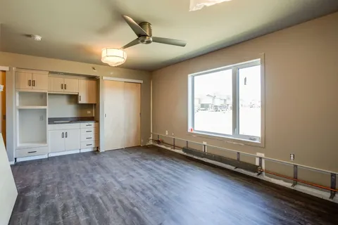 Empty room with a kitchenette, window and ceiling fan
