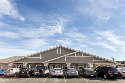 Building with a covered entrance behind a row of parked cars