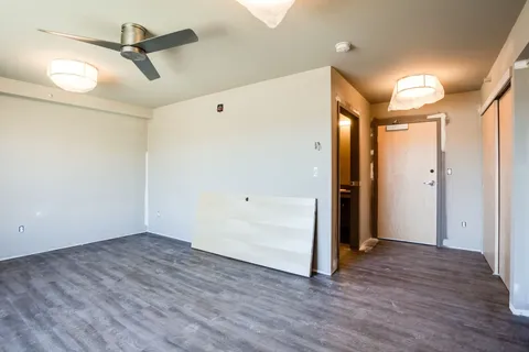 Empty room with grey flooring, a ceiling fan and wooden doors