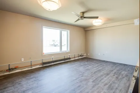 Empty room with a large window, ceiling fan and grey flooring