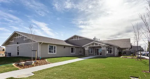 Single-storey building with a covered porch and a broad lawn