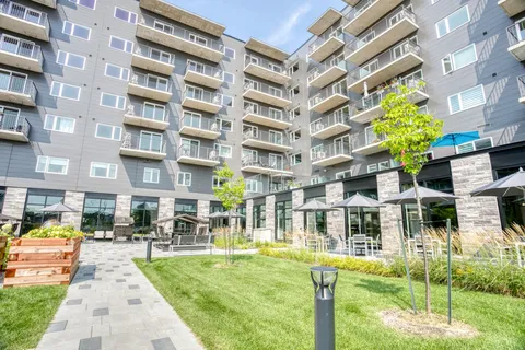 Residence balconies overlooking a lawn, paths and sheltered seating.
