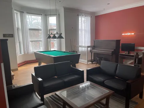 Room with black sofas, a billiards table, piano and television