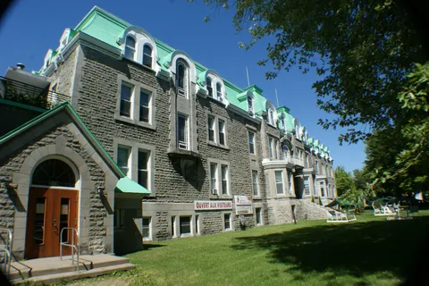 Stone residence with green roofs, tall windows and a lawn