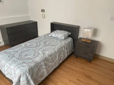 Bedroom with a single bed, bedside cabinet and wooden flooring