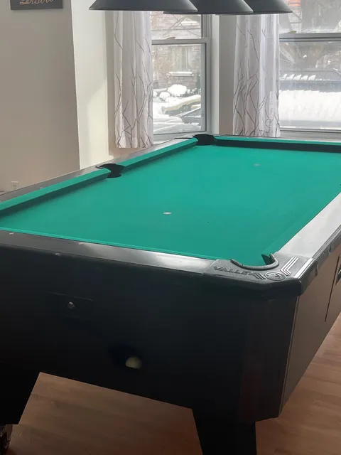 Billiards table beside a curtained window