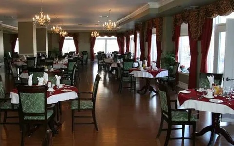 Dining room with green chairs, round tables, red curtains and chandeliers