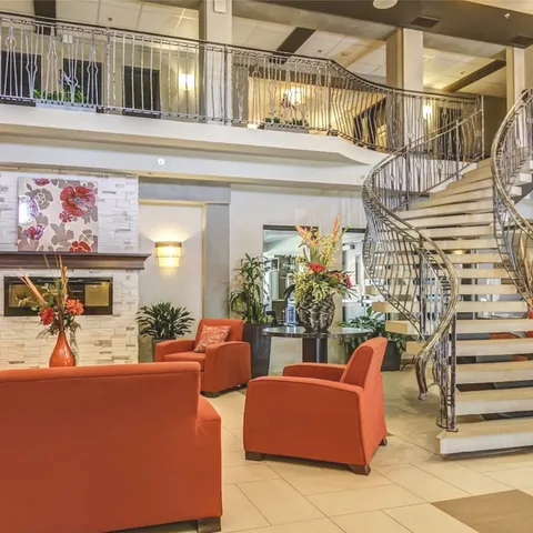Lounge with armchairs beneath an open upper-floor gallery.