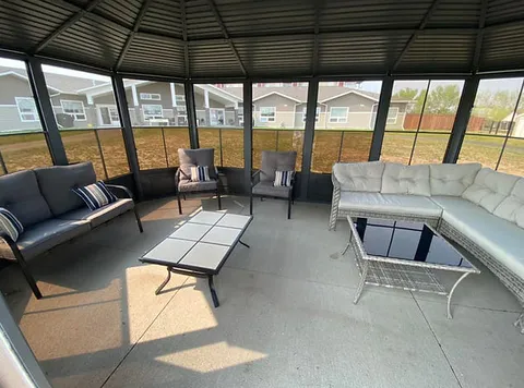 Screened gazebo with sofas, chairs and glass-topped tables.