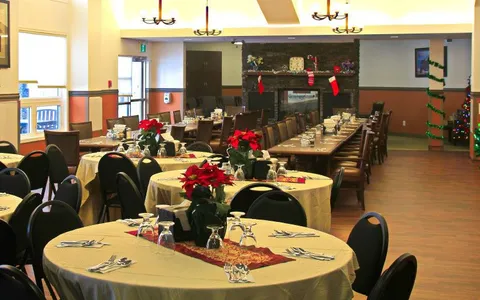 Dining room with set tables, chairs and a stone fireplace.