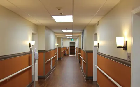 Hallway with doors, wall lights and handrails.