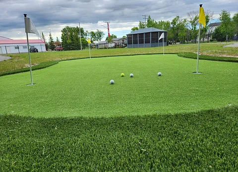 Outdoor putting green with flags beside a gazebo.