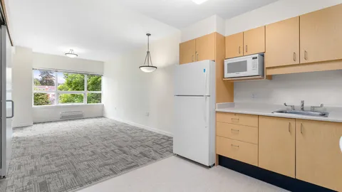 Empty room with a kitchenette, fridge, microwave and large window
