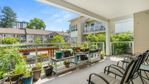 Covered balcony with potted plants and outdoor chairs overlooking a courtyard