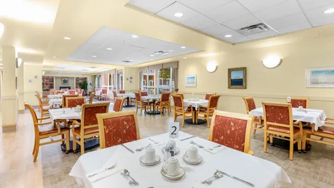 Dining room with white tablecloths, red upholstered chairs and large windows