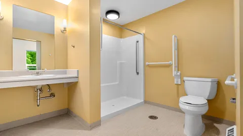 Bathroom with a sink, accessible shower, toilet and grab rails