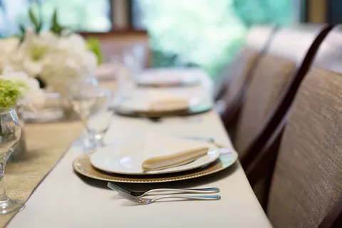 Private dining table set with plates, cutlery and flowers.