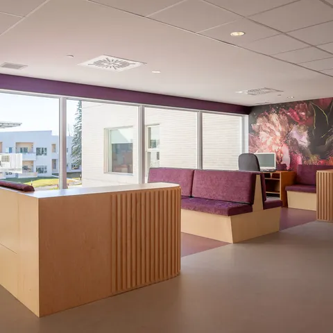 Purple upholstered seating beside windows and a desk