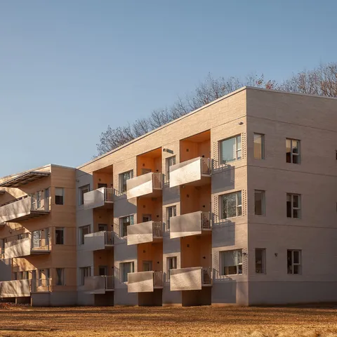 Pale brick residence wing with balconies beside a lawn