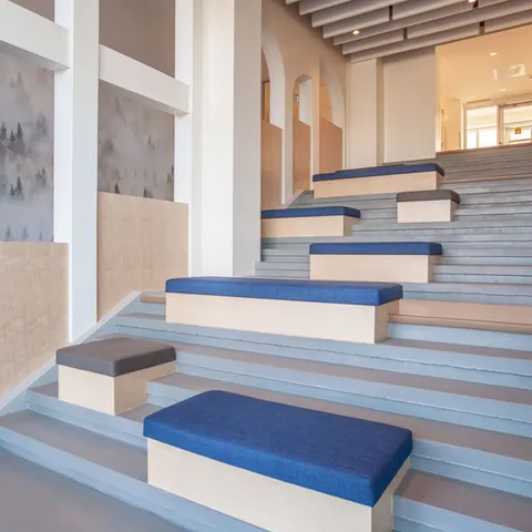 Wide staircase with blue seating cushions and wall alcoves