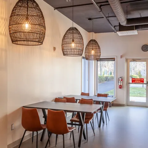 Tables and brown chairs beneath woven pendant lamps