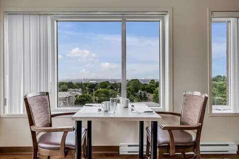 Table set with cups and glasses beside two chairs and a large window