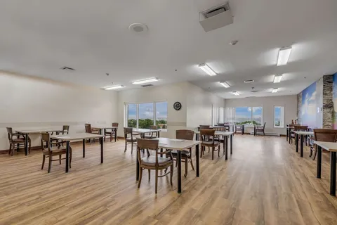 Room with square tables, wooden chairs and large windows