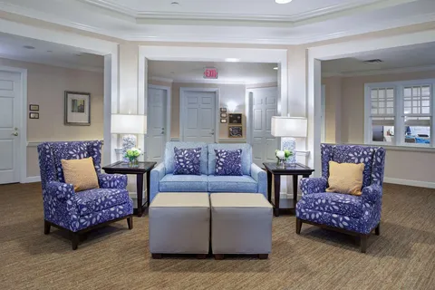 Sitting area with a blue sofa, patterned armchairs and two ottomans.