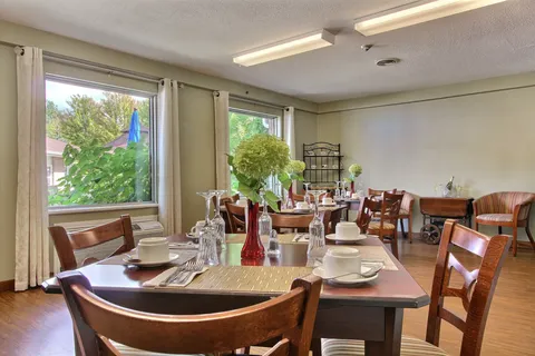Private dining room with a set table and chairs beside large windows.