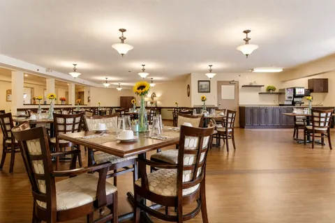 Dining room with wooden tables and chairs beneath ceiling lights.