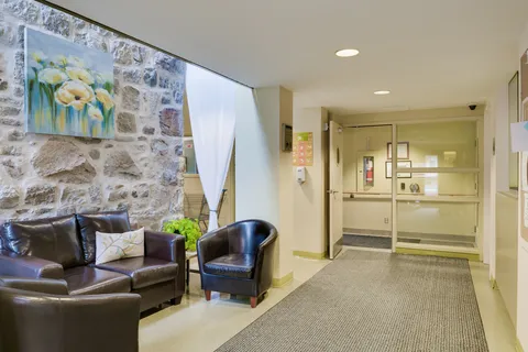 Entrance lobby with glass doors, leather seating and a stone wall