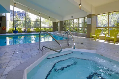 Indoor swimming pool and hot tub beside large windows.