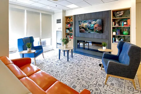Lounge with sofas, armchairs, bookshelves and wall television.