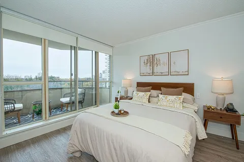Bedroom with a bed beside windows and balcony doors.