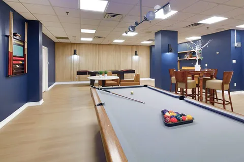 Billiards table beside shelving and tables in a games room.