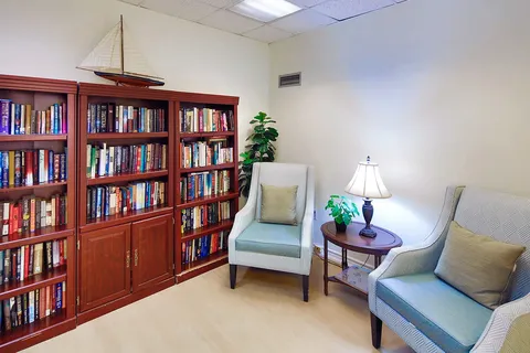 Library corner with bookcases and two armchairs.