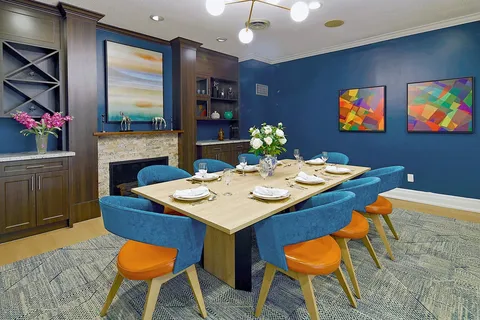Private dining room with a set table, blue chairs and fireplace.