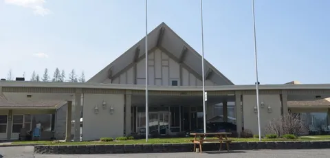 Residence entrance with a peaked roof, flagpoles and a bench