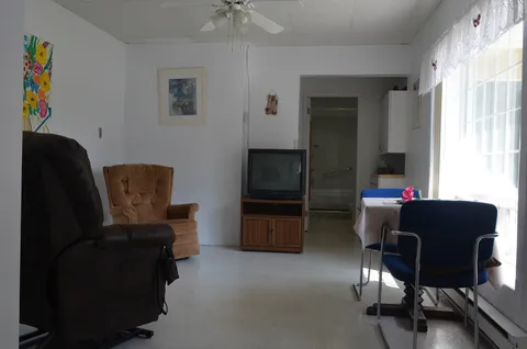 Room with recliners, a television, table and chairs beside large windows