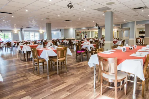 Dining room with rows of tables, chairs and large windows.