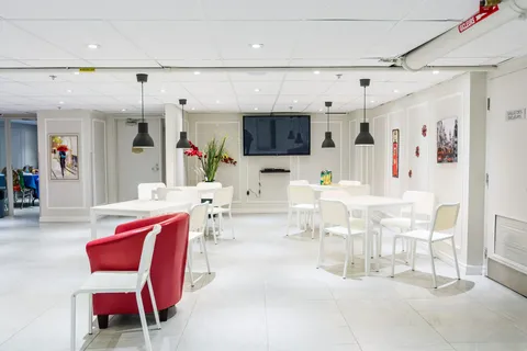 Cafe seating area with white tables and chairs and red armchairs.