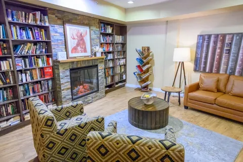 Library lounge with bookshelves, seating and fireplace.